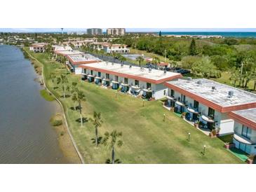 An aerial view of a waterfront condo complex with manicured lawns and mature palm trees at 26 Ocean Palm Villa S # 26, Flagler Beach, FL 32136