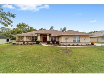 Charming single-story home with a manicured lawn, tasteful landscaping and a vibrant red front door at 10458 Sw 52Nd Ct, Ocala, FL 34476