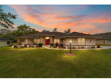 Charming single-story home with a manicured lawn, tasteful landscaping and a vibrant red front door at 10458 Sw 52Nd Ct, Ocala, FL 34476