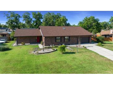 Charming single-story brick home featuring a well-manicured lawn and a welcoming red front door at 2030 Se 32Nd Ln, Ocala, FL 34471