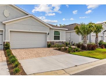 Charming home featuring a neutral exterior, paver driveway, stone accents and fresh landscaping at 5237 Nw 48Th Pl, Ocala, FL 34482