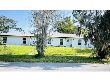 Charming single-story home with white exterior, well-manicured lawn, and mature trees at 251 Celery Cir, Oviedo, FL 32765