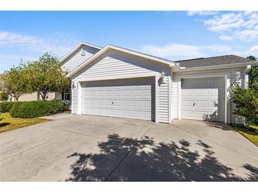Exterior of a charming home showcasing a three-car garage and well-maintained landscaping at 2297 Montbrook Pl, The Villages, FL 32162