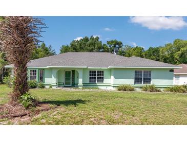 Charming single-story home featuring a well-maintained lawn, mature trees, and a lovely light green exterior at 3968 Sw 131St Place Rd, Ocala, FL 34473