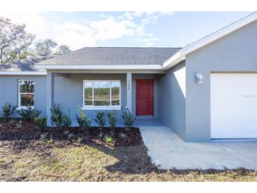 Charming single-story home featuring a red front door and a well-maintained, landscaped yard at 8900 Sw 138Th Ln, Ocala, FL 34473
