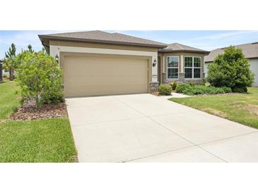 Home exterior showing a two-car garage, landscaped yard, and concrete driveway at 9478 Sw 52Nd Loop, Ocala, FL 34481
