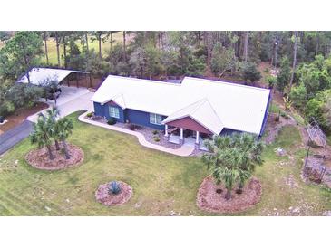 Stunning aerial view of a home with a metal roof, lush landscaping, and a covered parking area at 112 Reedy Creek Dr, Frostproof, FL 33843