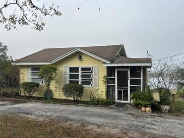 Yellow house with a screened porch and landscaped yard at 1120 S Scenic Hwy, Lake Wales, FL 33853