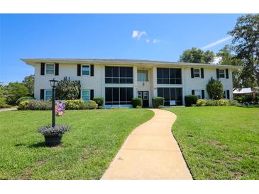 Well-maintained two-story condo building featuring a lush lawn and inviting walkway, with black shutters at 711 Springer Dr # 2, Lake Wales, FL 33853