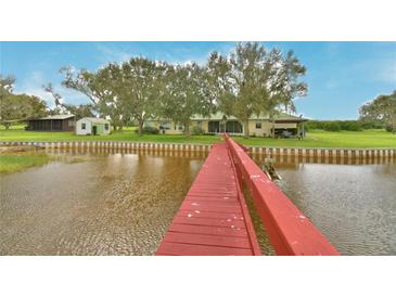 View down red wooden dock of waterfront home with green roof, backyard, and canal views at 1301 S Lake Reedy Blvd, Frostproof, FL 33843