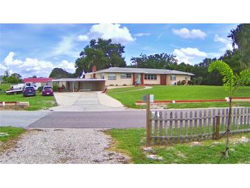 Charming single-story home featuring a carport, well-manicured lawn, and a classic picket fence at 301 S Clinch Lake Blvd, Frostproof, FL 33843