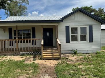 Charming exterior view features a front porch with wooden steps and railings and a freshly painted facade at 111 D St, Frostproof, FL 33843