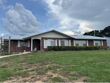 Charming brick home featuring a metal roof, neat landscaping, and a welcoming front porch at 400 W 4Th Ct, Frostproof, FL 33843