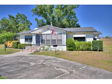 Charming single-story home featuring a well-maintained lawn, mature trees, and an American flag at 509 N Scenic Hwy, Frostproof, FL 33843