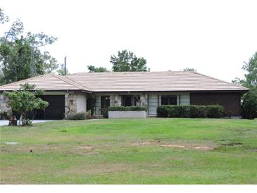 Charming single-story home with stone accents, well-manicured landscaping, and a spacious front yard at 7591 Limonia Dr, Indian Lake Estates, FL 33855