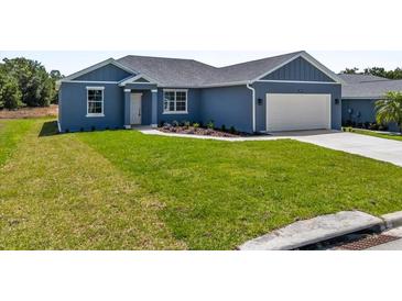Charming single story home with a blue exterior, attached garage, and green grass at 4550 Fairway Oaks Dr, Mulberry, FL 33860