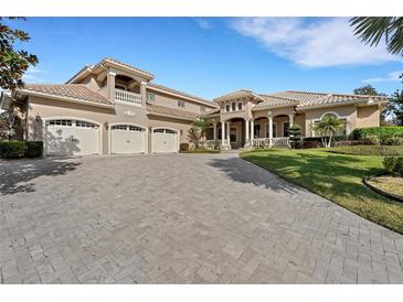 Elegant home featuring a paver driveway, three-car garage, and covered entryway with decorative columns at 6487 Ashley Dr, Lakeland, FL 33813