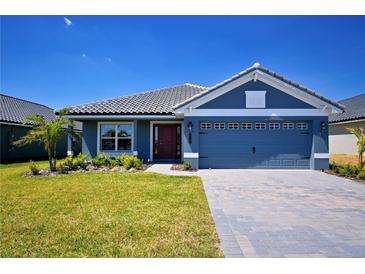 Charming single-story home with a blue exterior, well-manicured lawn, and a gray tiled roof under a clear blue sky at 5120 Villa Crest Way, Auburndale, FL 33823