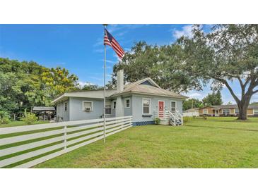 Charming single-story home with a red door and a white picket fence under a blue sky at 1705 Davis Ave, Bartow, FL 33830