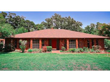 Charming brick home featuring a red door and manicured landscaping at 4428 Sugartree E Dr, Lakeland, FL 33813