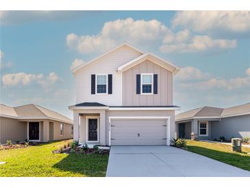 Charming two-story home featuring a gray facade, black shutters, and a two-car garage at 2214 Oldham Ct, Haines City, FL 33844