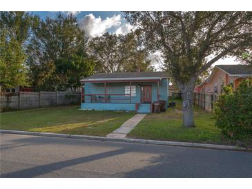 Charming, light-blue single story home features a covered front porch and a well-maintained lawn at 506 N Wales Dr, Lake Wales, FL 33853