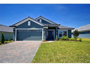 Beautiful single-story home with a well-manicured lawn, brick paver driveway, and a two-car garage at 5126 Villa Crest Way, Auburndale, FL 33823