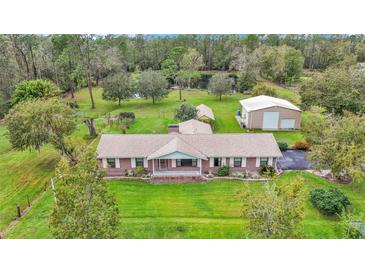Expansive property featuring a brick home, large lawn, detached garage, and picturesque pond at 9240 Moore Rd, Lakeland, FL 33809