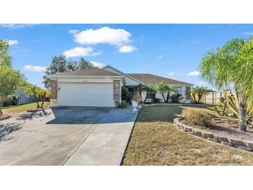 Charming single-story home with a well-manicured lawn, mature palm trees, and a two-car garage on a sunny day at 7525 Jessamine Dr, Lakeland, FL 33810