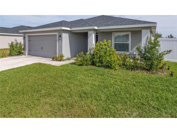 Single-story house with gray siding, gray garage door, and well-manicured lawn at 1225 Third Ct, Eagle Lake, FL 33839