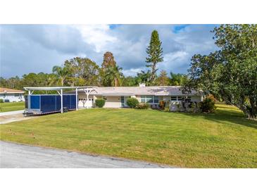 Charming single-story home featuring a spacious front yard and attached carport at 6029 Avocado Dr, Indian Lake Estates, FL 33855