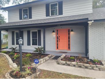 Two-story house with gray painted brick, a coral door and landscaping at 1305 Avenue S Nw, Winter Haven, FL 33881