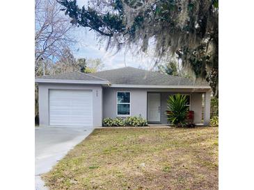 Gray house with a white door, landscaped yard, and attached garage at 520 Green Cir, Fort Meade, FL 33841