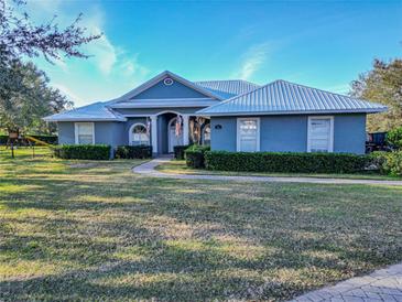 Single-story home with metal roof, manicured lawn, and paved driveway at 111 Arbor Way, Auburndale, FL 33823