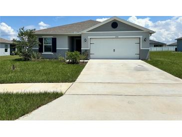 Gray house with white garage door and green lawn at 2300 Crossandra St, Mascotte, FL 34753