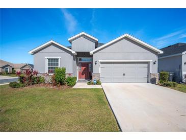 Gray house with red door, two-car garage, and landscaped lawn at 4340 Reding Way, Lakeland, FL 33813