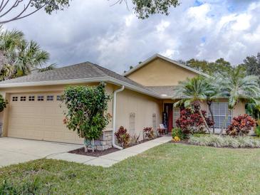 Tan house with a two-car garage, landscaping, and a welcoming entrance at 731 Lake Clark Ct, Lakeland, FL 33813
