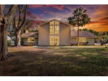 Two-story house with a large yard, mature trees, and a sunset backdrop at 1118 Cypress W Pt, Winter Haven, FL 33884