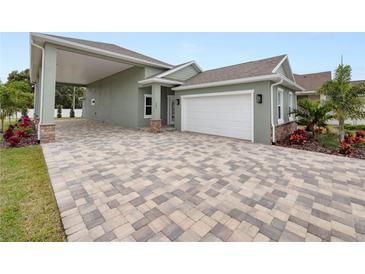 Green house with white garage door, paver driveway, and covered porch at 161 Laynewade Rd, Polk City, FL 33868