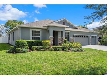 Charming single-story home featuring a three-car garage, manicured lawn, stone accents, and inviting entryway at 252 Magneta Loop, Auburndale, FL 33823