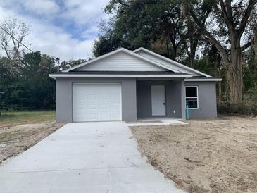 Newly constructed one-story home with gray exterior, white garage door, and a concrete driveway at 1108 Crestview Ave, Lakeland, FL 33805