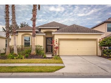 One-story house with beige walls, a two-car garage, and lush landscaping at 2507 Torrens Dr, Lakeland, FL 33805