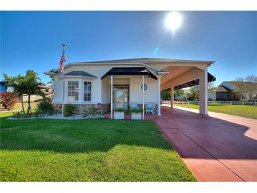 Single-story home with covered porch and carport, landscaped lawn, and red paver driveway at 1039 Motorcoach Dr, Polk City, FL 33868