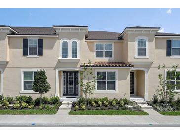 Tan two-story townhome with dark shutters, landscaping, and a tiled roof at 1559 Carey Palm Cir, Kissimmee, FL 34747