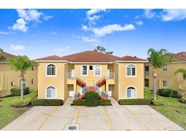 Tan two-story building with red staircases, surrounded by landscaping at 16202 Indian Creek Dr # 16202, Kissimmee, FL 34759