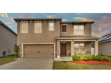 Two-story house with tan siding, brown roof and landscaping at 1915 Pristine Loop, Lakeland, FL 33811