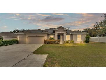 Tan house with solar panels, 2-car garage, and landscaped lawn at 212 Kissengen Park Dr, Bartow, FL 33830