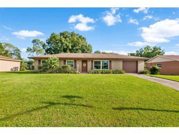 Charming home featuring a lush green lawn, well-maintained landscaping, and an attached garage at 123 Padgett N Pl, Lakeland, FL 33809