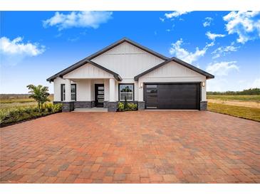 Modern farmhouse exterior boasts a brick driveway and attached garage at 2200 Mcclellan Rd, Frostproof, FL 33843