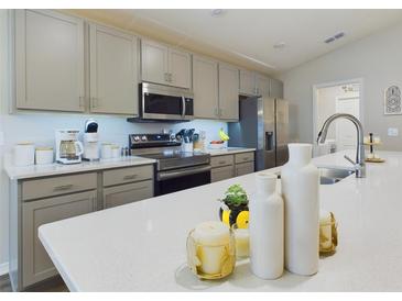 Bright kitchen features stainless appliances, gray cabinets, and white countertops at 2610 San Marco Way, Winter Haven, FL 33884